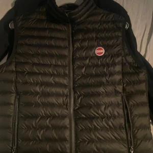 Svart dunväst från Colmar - Snygg svart dunväst från Colmar med dragkedja och logotyp på bröstet. Perfekt för lager-på-lager under kyliga dagar. Västen har en stilren design med quiltade detaljer och praktiska fickor med dragkedja. De är storlek S
