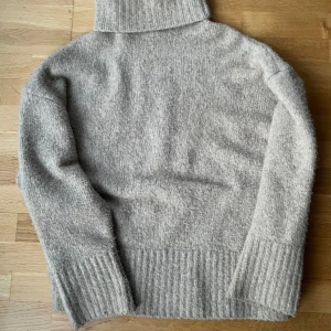 Beige stickad polotröja från Zara - Mysig beige stickad polotröja från Zara med lång ärm och breda ribbade muddar. Perfekt för kyliga dagar och enkel att matcha med olika outfits.