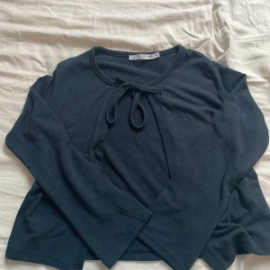Mörkblå långärmad tröja med knyt från 157 - Mörkblå långärmad tröja från 157 med rund halsringning och dekorativ knytning framtill. Tröjan är i mjukt material och har en enkel, stilren design som passar till mycket. Perfekt för dig som gillar en basic men ändå snygg look.