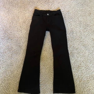 Svarta bootcut jeans - Svarta jeans med bootcut-passform. Byxorna har knapp och dragkedja framtill samt raka ben som blir vidare nedtill. 