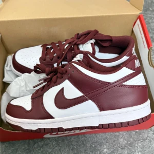 Nike Dunk Low röd och vit - Säljer ett par Nike Dunk Low i rött och vitt. Skorna har klassisk låg siluett, vit bas med röda overlays och matchande röd sula. Perfekta för dig som gillar streetwear och sneakers med stilren design. Super perfekt nu inför sommaren har flera andra par så dessa har inte kommit till användning 