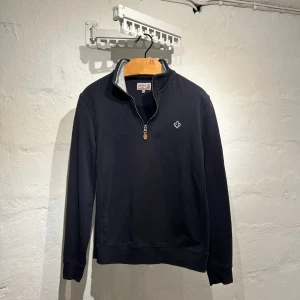 Mörkblå halvzip tröja från Morris - Säljer en stilren mörkblå långärmad tröja från Morris med halv dragkedja och liten broderad logga på bröstet. Perfekt för lager-på-lager och passar till många tillfällen. Storleken som står är  M men den sitter som S! Bara att ställa frågor om du undrar något!