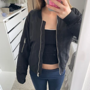 Svart bomberjacka  - En svart bomberjacka med silvriga detaljer! Perfekt för en cool och avslappnad stil. 