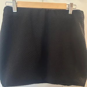 Svart strukturerad kjol från Amisu - En svart kortkjol från Amisu med strukturerat tyg och enkel design. Kjolen har en rak passform och är perfekt för dig som gillar stilrena plagg med lite textur.