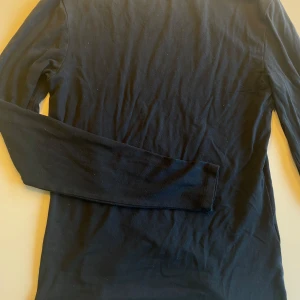 Svart långärmad tröja från 157 - En enkel och stilren svart långärmad tröja från 157. Perfekt basplagg i mjukt bomullsmaterial, passar till många olika outfits. Klassisk rund halsringning och smal passform.