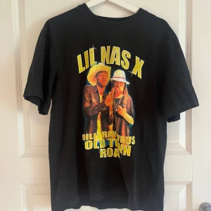 Svart Lil Nas X t-shirt från Divided - Cool svart t-shirt från Divided med stort Lil Nas X-tryck och texten 'Old Town Road' på framsidan. T-shirten har normal passform och korta ärmar. Perfekt för dig som gillar musik och streetstyle. PRIS GÅR ATT DISKUTERAS