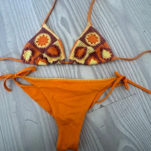 Orange virkad bikini från Calzedonia - Superfin orange bikini från Calzedonia med virkade detaljer i gult, orange och lila på överdelen. Underdelen är enkel och knyts i sidorna. Passar st 75B och S i underdel 