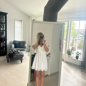 Vit omlottklänning med vida ärmar - Säljer en superfin vit omlottklänning med knyt i midjan och v-ringning. Endast använd en gång på avslutning i 9an🥰