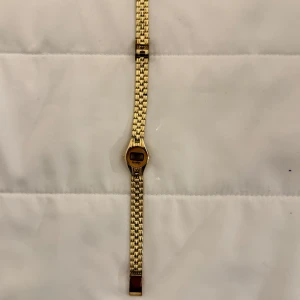 Guldig vintage damklocka med länkarmband - Säljer en stilren digital damklocka från Quartz i guld med länkarmband. Klockan har en oval urtavla och digital display. Perfekt accessoar för dig som gillar klassisk/vintage och tidlös design.