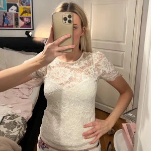Vit spetsblus från Gina Tricot - Säljer en söt vit spetsblus från Gina Tricot med blommigt mönster. Blusen har korta ärmar och är genombruten med fina spetsdetaljer. Perfekt att styla med jeans eller kjol för en fräsch look.