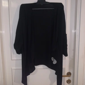 Svart kofta från Amisu - Säljer en svart kofta från Amisu i storlek M. Koftan har en lös passform och är öppen framtill utan knappar eller dragkedja. Perfekt att slänga över en topp eller t-shirt för en enkel och stilren look.