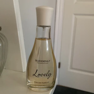 Suddenly Fragrances Lovely Eau de Parfum - En elegant parfym med namnet Lovely från Suddenly Fragrances. Flaskan är genomskinlig med mjuka former och har ett vitt lock. Innehållet är ljust och flaskan rymmer Eau de Parfum.