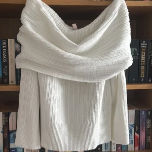 Vit offshoulder stickad tröja Nelly - Superfin vit stickad tröja från Nelly i offshoulder-modell. Tröjan har bred krage som vilar över axlarna och ribbad struktur. Perfekt till jeans eller kjol för en trendig look. Mjuk och skön, passar både till höst och vinter. 