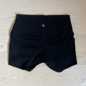 Svarta define shorts från Lululemon - Säljer ett par svarta,  träningstights-shorts från Lululemon. De är tillverkade i ett stretchigt syntetmaterial och har en tight passform. 😊