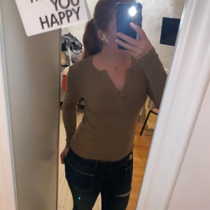 Brun ribbad långärmad tröja - Säljer en brun långärmad tröja med ribbad struktur och v-ringad hals. Tröjan har en slim passform och är perfekt för lager-på-lager. Enkel och stilren design som funkar till många outfits.