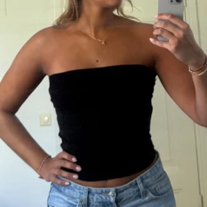 Svart tubtopp - En svart bandeau tubtopp från H&M i ribbad bomullsmix. Toppen är ärmlös och axelbandslös, sitter tight 