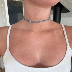 Blå pärlchoker med guldlås - Superfin choker med små blå pärlor i olika nyanser och ett litet guldfärgat lås. Halsbandet sitter tajt runt halsen och ger en fräsch och somrig vibe. Perfekt för dig som gillar färg och vill ha något unikt och handgjort. kontakta mig med önskade färger och storlek! priset är förhandlingsbart ☺️