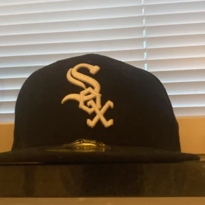 Chicago sox keps svart  - Svart 59FIFTY keps från New Era med Chicago White Sox-logga broderad i vitt framtill och MLB-logga bak. Klassisk flat peak och strukturerad passform. Perfekt för dig som gillar sportig streetstyle.
