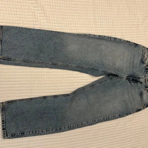Blå vintage jeans från Grunt - Säljer ett par blå vintage-inspirerade jeans från Grunt . Jeansen har rak passform, klassisk femficksdesign och är tillverkade i bomull. Perfekta för dig som gillar en avslappnad och tidlös look.
