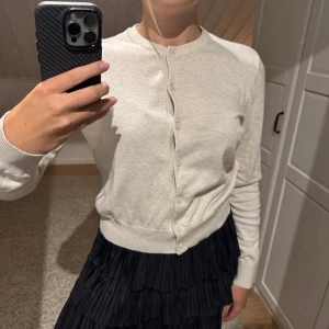 Beige kofta från H&M med knappar - En stilren beige kofta från H&M med rund halsringning, prefekt till hösten. Grym att slänga över en topp eller klänning för en clean look.