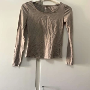Beige långärmad topp från 157 - Enkel och stilren beige långärmad topp från 157. Modellen har rund halsringning och är figurnära i passformen. Perfekt att matcha med jeans eller kjol för en clean look.