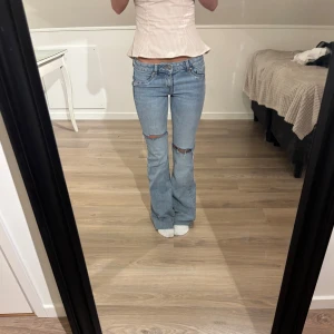 Bootcut jeans med slitna knän - Snygga ljusblå bootcut jeans med slitna detaljer vid knäna. 