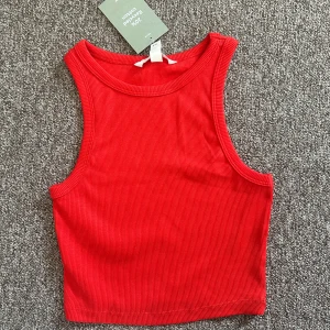 Röd ribbad linnetopp från H&M - Snygg röd croppad linnetopp från H&M i ribbad bomullsmix. Den är ny med prislapp då den var för liten. Det är storlek XS. 