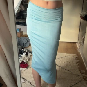Ljusblå ribbad långkjol från Shein - Säljer en ljusblå ribbad långkjol från Shein i storlek XS. Kjolen har en tight passform och en snygg slits på sidan som ger extra edge. Perfekt för dig som gillar stilrena och bekväma plagg med lite extra detalj.