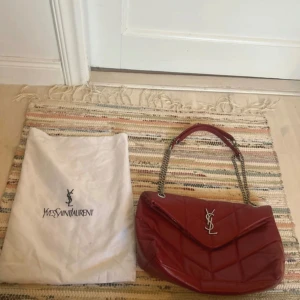 Röd quiltad axelväska - Säljer en snygg röd axelväska quiltad design och silverfärgad kedjerem. Perfekt storlek. Väskan är aldrig använd men hade några slitningar när jag köpte den. Liknade.