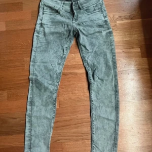 Grå jeans från G-Star RAW - Säljer ett par grå jeans från G-Star RAW med tvättad look. Byxorna har fem fickor, dragkedjegylf och klassisk jeansdesign. Passformen är smal och materialet är stretchigt för extra komfort. Priset är inte hugget i sten!