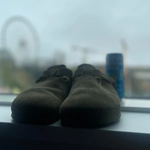 Birkenstock Boston i mocka - Säljer ett par klassiska Birkenstock Boston i beige mocka. Skorna har en rund tå, justerbart spänne och platt sula. Perfekta för en avslappnad stil och riktigt sköna att gå i. Priset kan diskuteras!😀