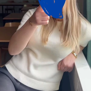 Vit stickad kortärmad tröja - Säljer en stilren vit stickad tröja med korta ärmar och rund halsringning. Tröjan har ribbade muddar vid ärmslut och nederkant, vilket ger en snygg och enkel look. Perfekt att matcha med både jeans och kjol.