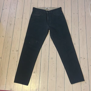 Mörklbå  jeans från Stone Island - Säljer ett par mörklbå jeans från Stone Island med klassisk femficksdesign och rak passform. Byxorna har en knappgylf och den ikoniska Stone Island-loggan på bakfickan. Perfekta för dig som gillar stilrena och tidlösa jeans.