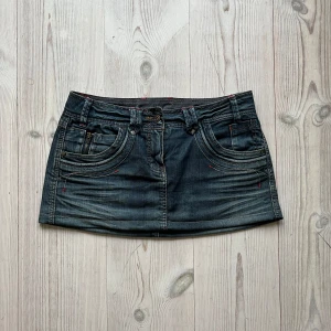 Blå lågmidjad jeanskjol  - Lågmidjad jeanskjol från Camaieu i fint skick. Kan inte hitta storlek men skulle säga S/M. Tvärs över midjan är det 38 cm och den är ca 27 cm lång. Använd gärna köp nu!