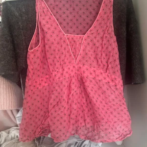 Rosa blommig vintage linnetopp  - Säljer en söt rosa linnetopp från Rozzato med små blommiga prickar och v-ringad hals. Toppen är ärmlös och har en luftig, lätt transparent design med volangliknande fall. Perfekt för varma dagar! Står ingen storlek i toppen men skulle tippa på ungefär M. Toppen är vintage och från Italien! Skriv vid minsta fråga 💗