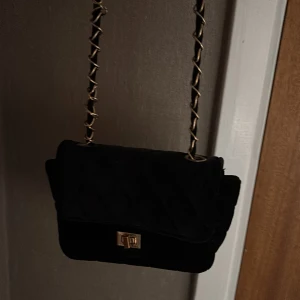 Svart quiltad axelväska med guldkedja - 100kr