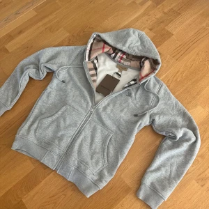 Burberry zip hopdie - Säljer denna helt nya med etikett Burberry zipen/koftan/hoodien som är sjukt stilig. Den är i storlek M. Säljer då jag är i behov av pengarna men den är riktigt fet nu till våren! 