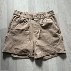 Beiga mjukisshorts  - Snygga beiga mjukisshorts med elastisk midja och fickor både fram och bak. Perfekta för varma dagar och har en avslappnad passform. Tillverkade i mjukt material som känns skönt mot huden.
