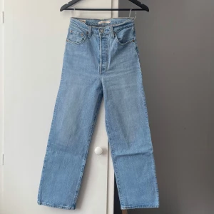 Levi's Ribcage-jeans - Ljusblåa Levi's Ribcage-jeans, rakmodell i storlek W26. Femficksmodell • Knappgylf • Använda ett fåtal gånger, fint skick. Innerbenslängd: cirka 66 cm.