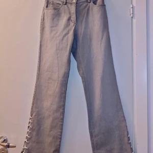 Jeans med snörning  - Asss snygga omsydda jeans! Perfekt grå färg och material, samt har bokstaven M på bakfickan som extra detalj! 