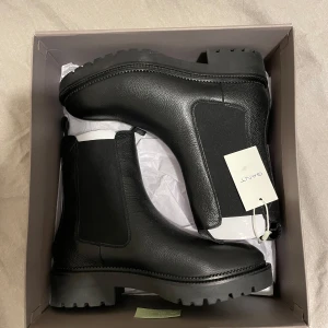 Svarta Chelsea boots från Gant - Säljer ett par svarta Chelsea boots från Gant i äkta skinn. Skorna har elastiska paneler på sidorna och kraftig platt sula för en cool look. Perfekta för dig som vill ha stilrena boots med robust känsla. Helt nya aldeig använda som ni kan se från Gant butiken😍 Ordpris 2099kr