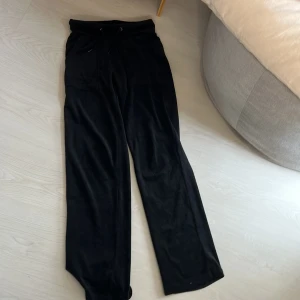 Svarta mjukisbyxor med dragsko - Säljer ett par svarta mjukisbyxor med bred resår i midjan och snörning. Byxorna har raka ben och två fickor framtill. Perfekta för en avslappnad stil och riktigt sköna att ha på sig.