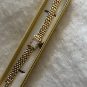 Guldfärgad fyrkantig damklocka från Bovou - Stilren guldfärgad klocka från Bovou med fyrkantig vit urtavla och länkarmband i metall. Klassisk design som passar perfekt till student eller sommarens tillfällen. Enkel och elegant accessoar. Klockan har lite defekter men syns ej då det är på baksidan.