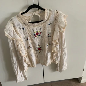 Beigeljuslångärmadblus volang vid axlar röda blommor och broderi anglaise - Fin blus