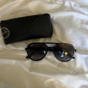 Svarta solglasögon från Ray-Ban - Snygga svarta solglasögon från Ray-Ban med klassisk pilotform och mörka glas. Ray-Ban-logga på linsen. Kommer med original svart fodral.