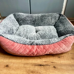 Rosa och grå hund eller katt bädd från Harmony - Mysig husdjurbädd i rektangulär form med mjuk grå insida och quiltad rosa utsida. Tillverkad i 100% polyester, perfekt för att ge ditt husdjur en bekväm plats att vila på. Bädden har höga kanter och en fluffig botten.