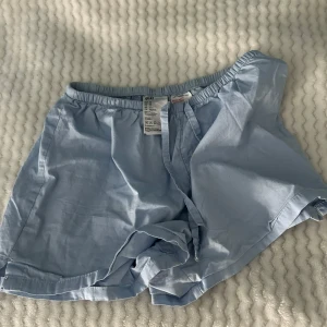 Ljusblå linne shorts   - Lätta och bekväma ljusblå shorts från H&M i bomull. De har elastisk midja och klassisk passform, perfekta för varma dagar eller som mjuka sovshorts.