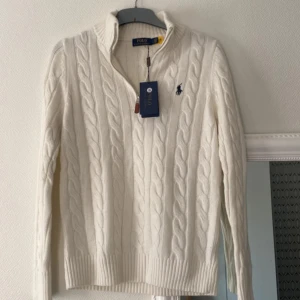 Ralph Lauren half zip - Säljer en klassisk vit kabelstickad tröja från Polo Ralph Lauren med hög krage och broderad logga på bröstet. Storlek S ( taggen är inte kvar ) endast använt några få gången aldrig tvättad