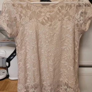 Beige spetsblus från Dorothy Perkins - Säljer en söt beige/rosa spetsblus från Dorothy Perkins. Blusen har korta ärmar och är helt täckt av ett vackert blommigt spetsmönster. Priset går att diskuteras💕