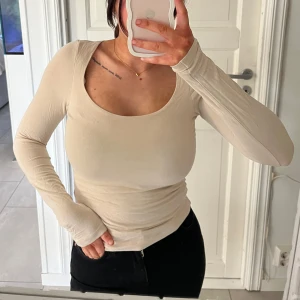 Beige långärmad topp med rund hals - Säljer en beige långärmad topp med rundad halsringning. Toppen är figurnära och har en enkel, stilren design som passar till mycket. Perfekt basplagg i garderoben och lätt att matcha med olika outfits.
